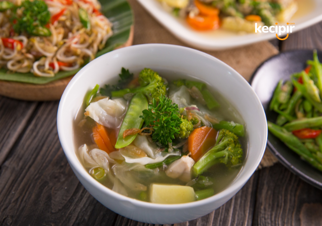 Foto srmangkuk sayur sop di atas meja bersama dengan hidangan lain